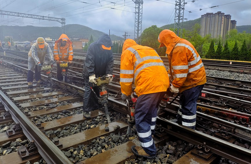 延安工務(wù)段職工雨中對線路幾何尺寸不良處所進(jìn)行整治。劉一帆攝