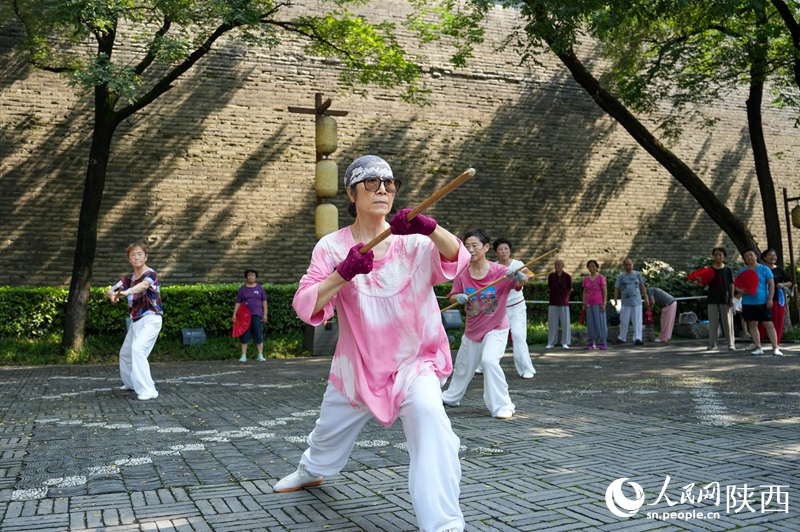 市民在西安城墻下的環(huán)城公園內(nèi)練習(xí)龍形鞭桿。李欣宇 攝